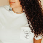 Person wearing a white t-shirt with text and a logo, against a neutral background